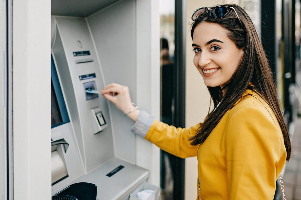 Ein Symbolbild einer Frau, die an einem Bankautomaten ihre Bankkarte verwendet.
