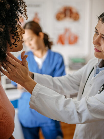 Eine Ärztin untersucht den Hals einer Patientin.