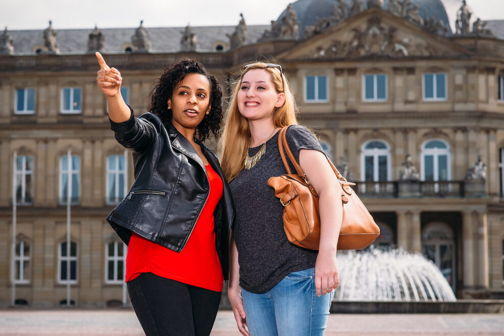 Zwei junge Frauen stehen in Stuttgart vor der Staatsoper.