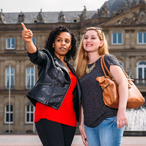 Zwei junge Frauen stehen in Stuttgart vor der Staatsoper.
